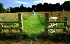女孩赤脚奔跑在农场围栏草坪上