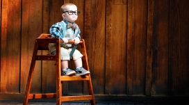 坐在高脚凳子上戴眼镜的小小外国“科学家”