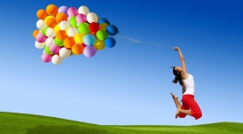 幸福-绿色草地上手拿五彩气球跳跃的女人