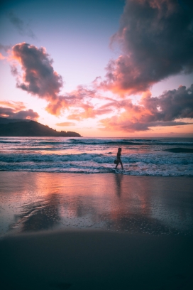 日落下海滩散步的女人