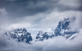 被云雾包围的雪山山峰风景图