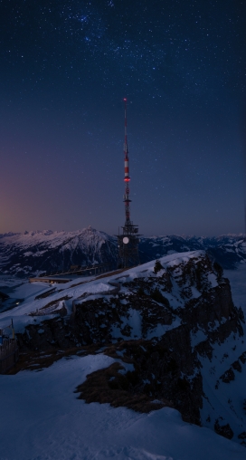 冬季星空下雪山上的信号发射塔
