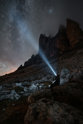 手持手电筒照射星空的徒步者