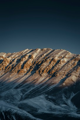 晨光轻抚覆雪山峦勾勒硬朗山体轮廓