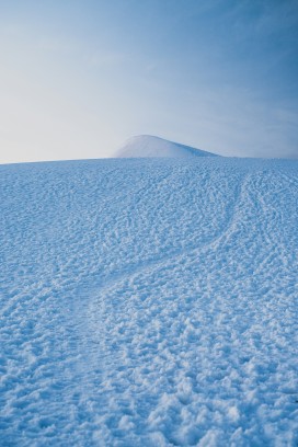雪原蜿蜒小径望向远方圆润雪丘旷野风光