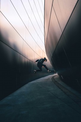 低角度仰拍黑衣男子现代金属建筑走廊跳跃动态街头摄影